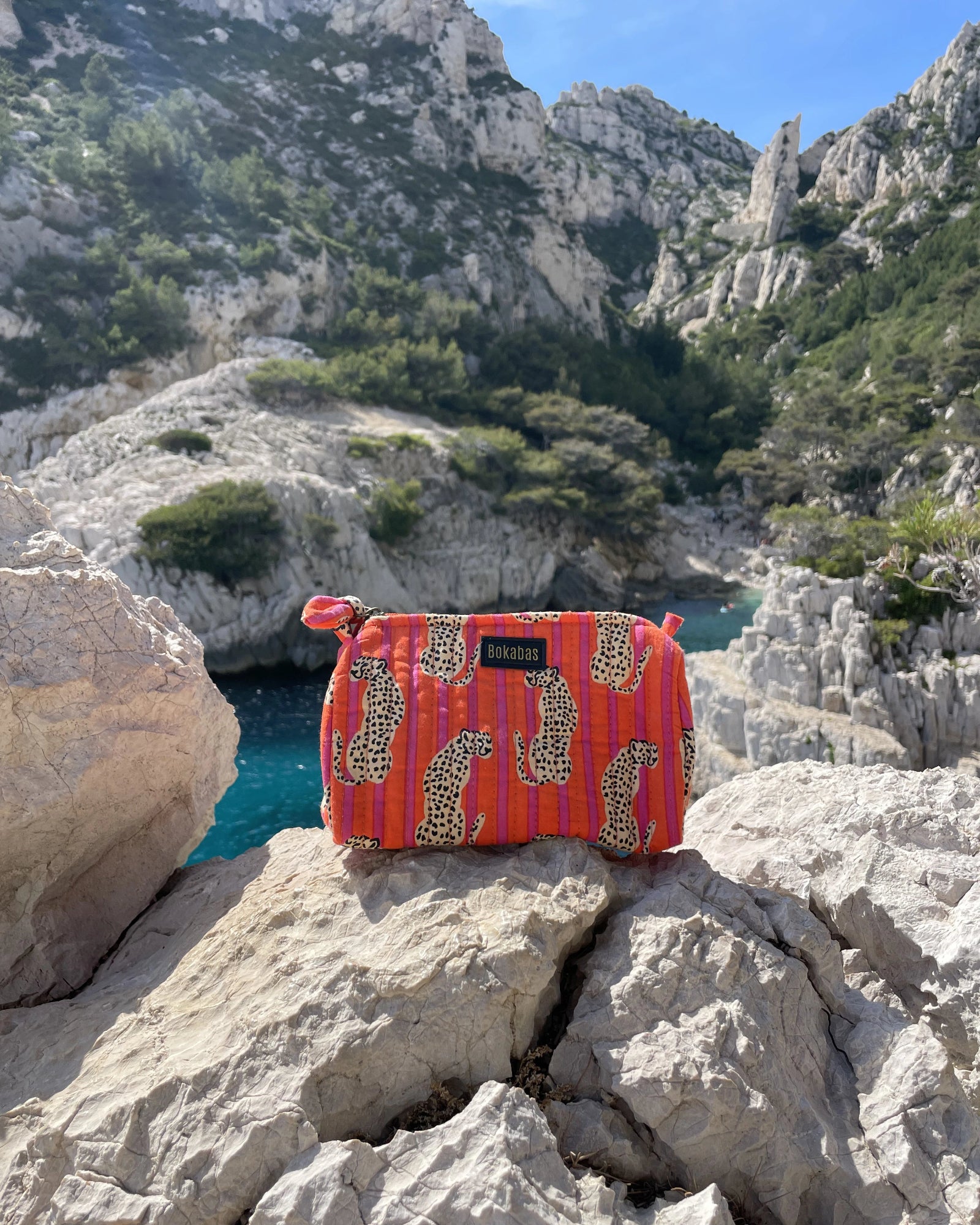 Trousse de toilette Bokabas, imprimé Guépard orange et rose, devant les falaises d'une calanque