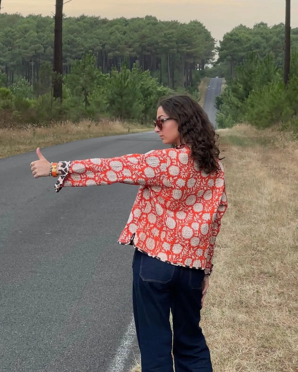 Veste matelassée orange Bokabas portée par une femme sur une route en pleine nature